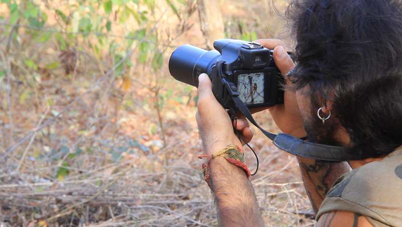 Photographer capturing nature with a DSLR camera in a woodland setting.