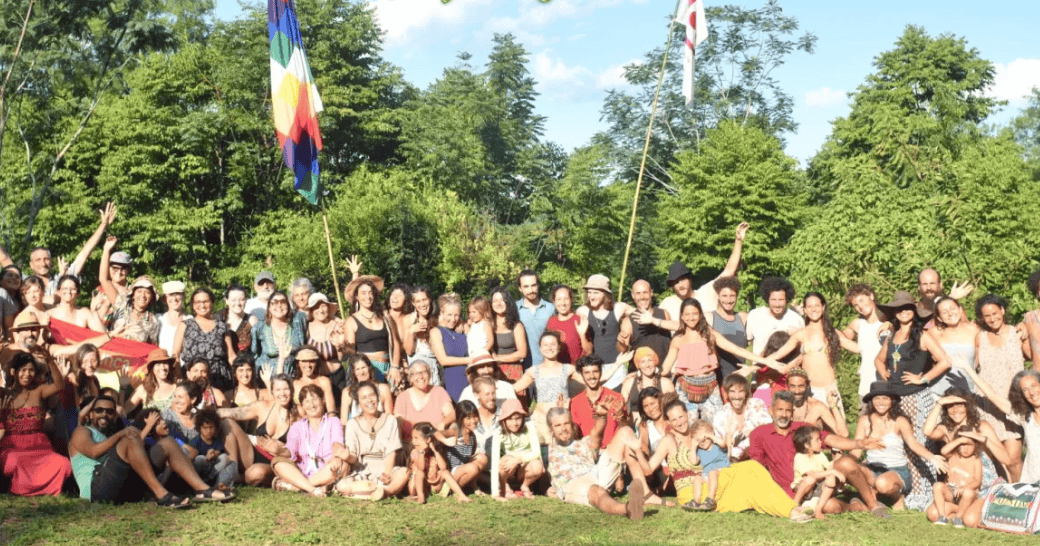 Large group of people outdoors with flags, celebrating community and sustainability.