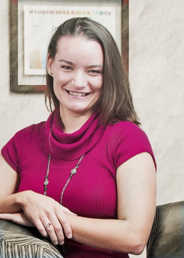 Young woman smiling at Eco Village, wearing a pink top and necklace.