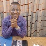 Professional man smiling at camera in meeting setting, warm atmosphere.