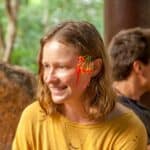 Portrait of a smiling woman at an eco village event with flower adornment.