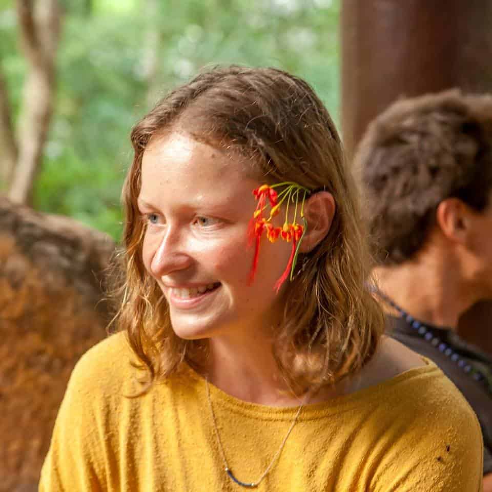 Portrait of a smiling woman at an eco village event with flower adornment.