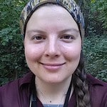 Portrait of a smiling woman outdoors in forest setting.