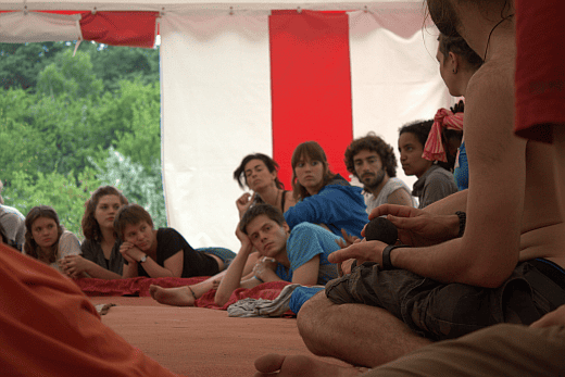 Group of diverse participants seated inside a tent at a conference.