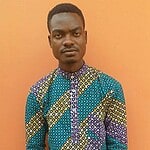 Portrait of a man in a colourful patterned shirt against an orange wall.