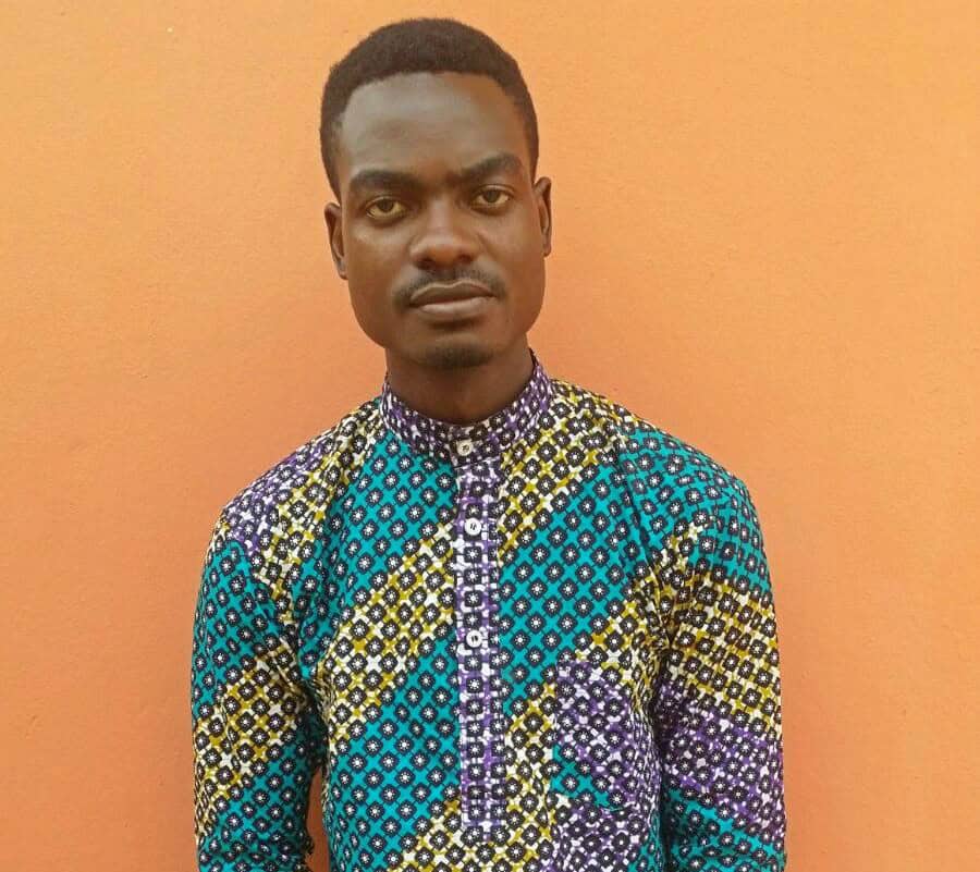 Portrait of a man in a colourful patterned shirt against an orange wall.