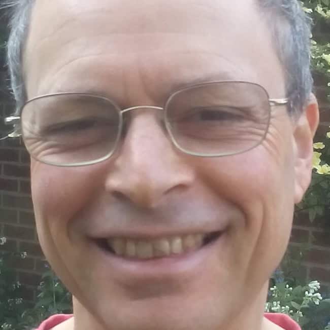 Friendly smiling man with glasses outdoors, SEO-friendly image for Global Ecovillage Network.