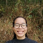 Smiling woman wearing glasses outdoors, close up selfie.