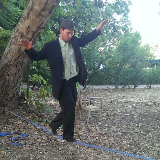 Man in a suit balancing on a blue line outdoors, nature background.