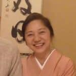 Smiling woman in pink top with neutral background.