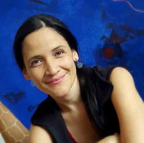 Portrait of a smiling woman in front of a blue background.