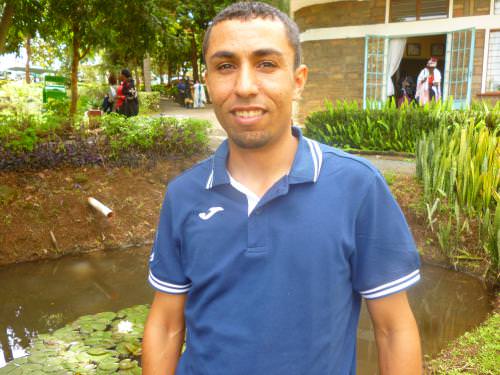 Man beside a pond in a campus setting for Global Ecovillage Network.