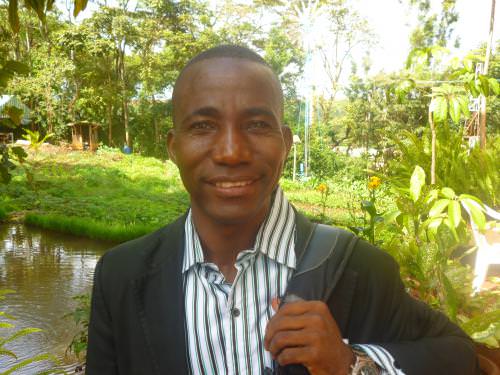 Portrait of a man in a garden with trees and water.