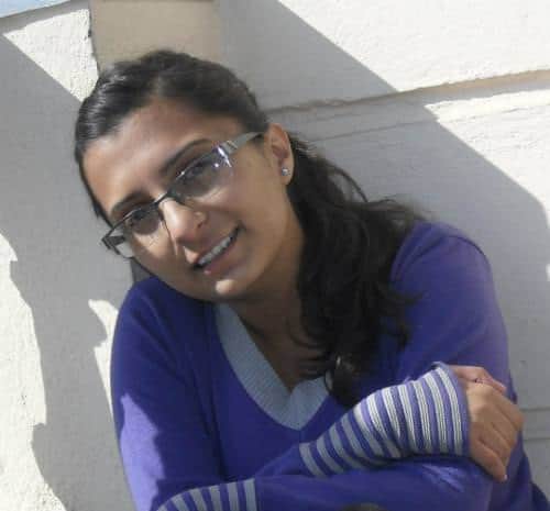 Portrait of a woman with glasses in a purple sweater.