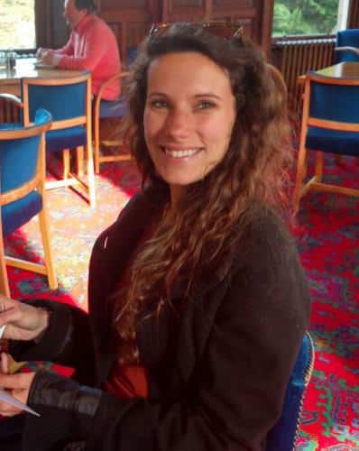 Portrait of Victoria Stallwood in a bright room with colorful chairs.