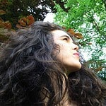 Portrait of a woman looking up with trees in the background.