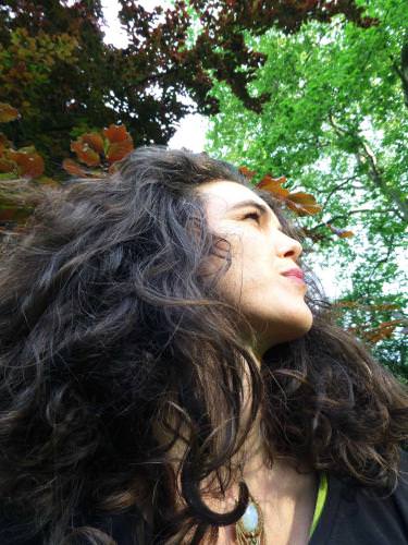 Portrait of a woman looking up with trees in the background.
