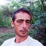 Portrait of a man outdoors in a natural, green setting.