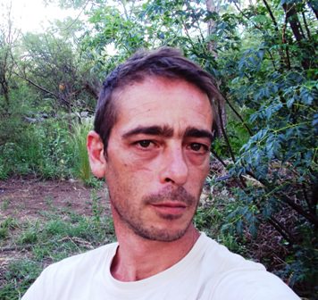 Portrait of a man outdoors in a natural, green setting.