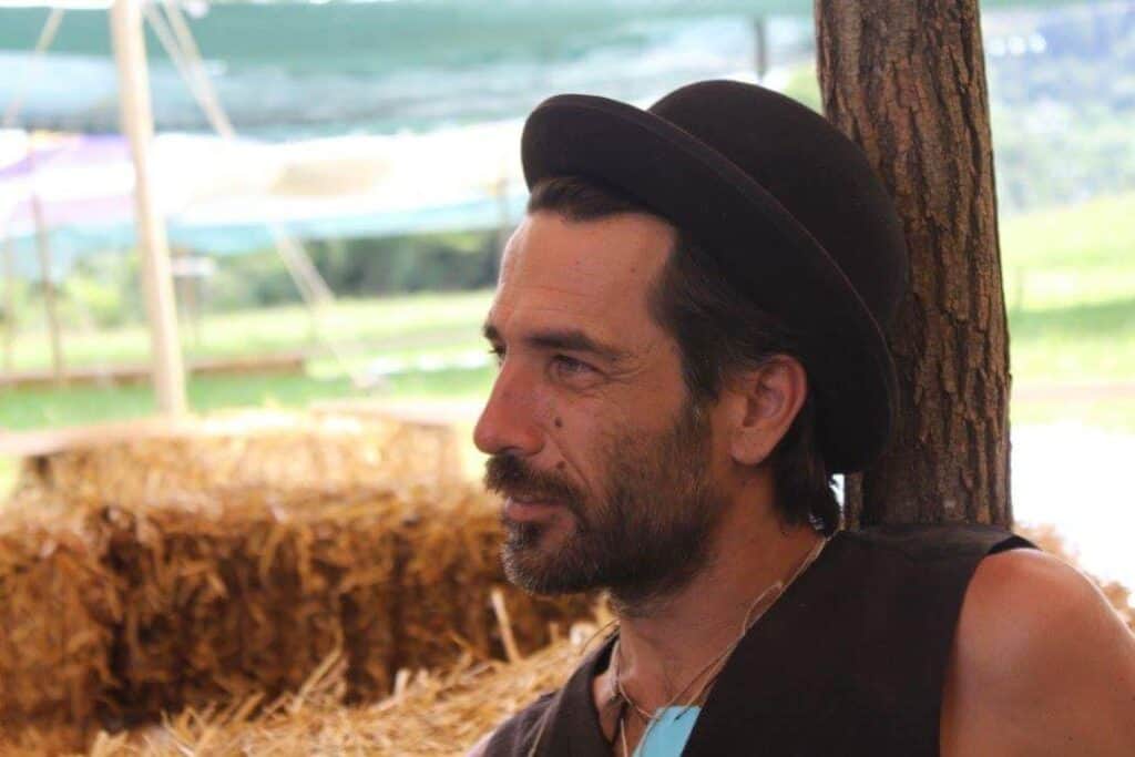 Riccardo Clemente at a rustic outdoor setting, straw bales and trees in the background.
