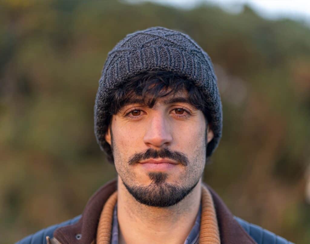 Portrait of a man wearing a beanie in natural outdoor setting.