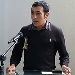 Man speaking at a podium with a microphone.