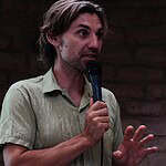 Speaker with microphone discussing sustainable communities at a Global Ecovillage Network event.