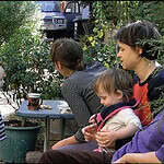 Group of people in a garden engaging with children and plants.