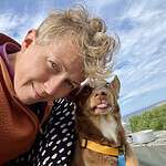 Emma Palmér with a small brown dog outdoors near the coast.