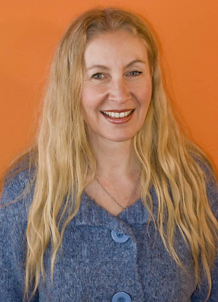 Portrait of a smiling woman with long blonde hair against an orange background.