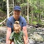Woman and child enjoying nature by a forest stream.