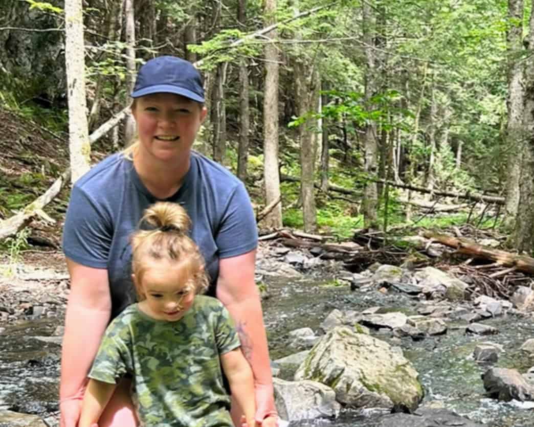 Woman and child enjoying nature by a forest stream.