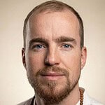 Portrait of a man with blue eyes and bead necklace.