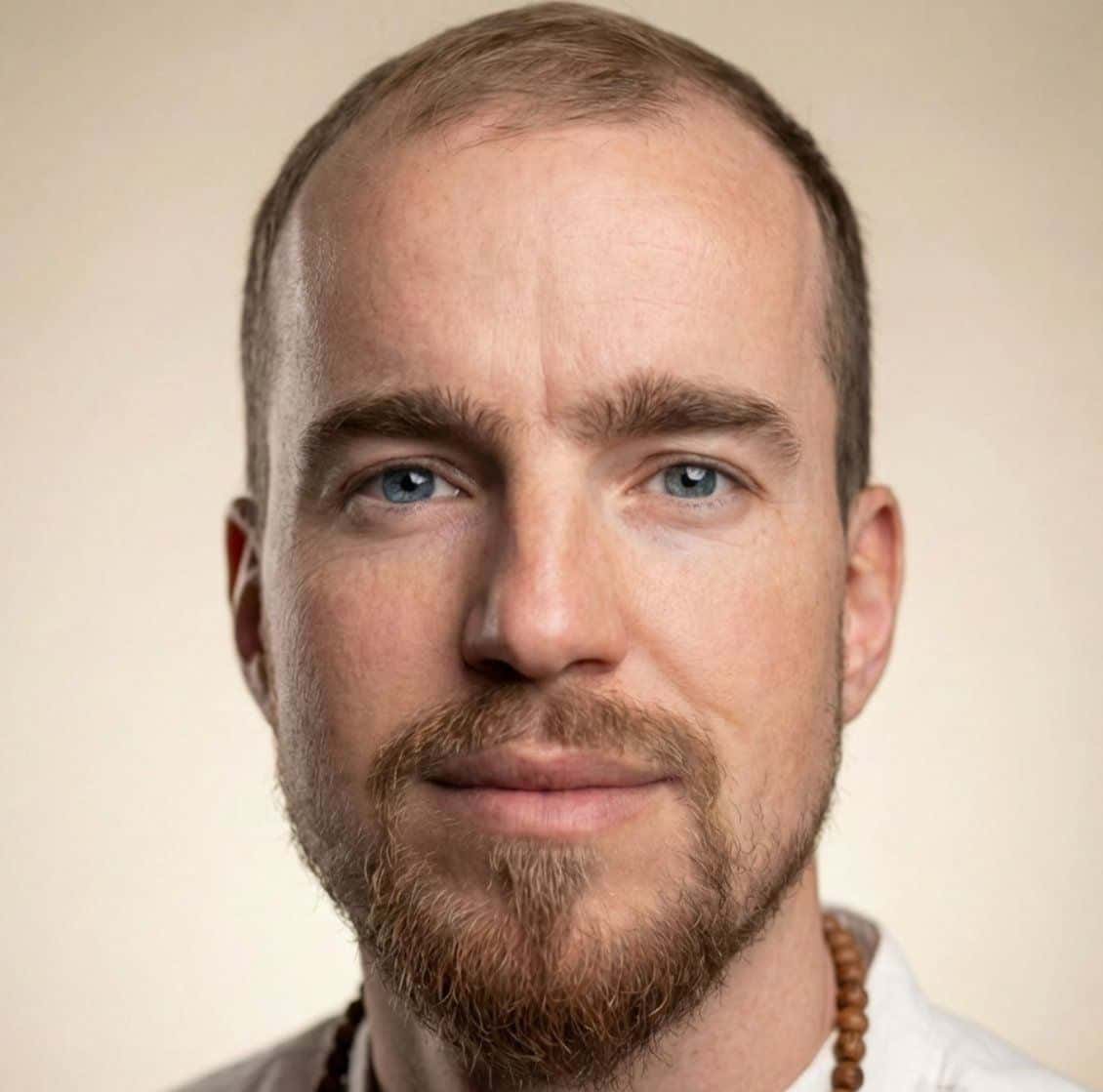 Portrait of a man with blue eyes and bead necklace.
