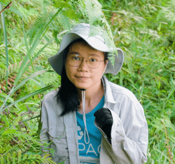 Woman in eco-friendly attire conducting field research in lush greenery.