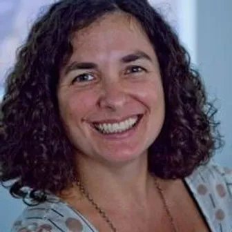 Smiling woman with curly hair in a light scarf.