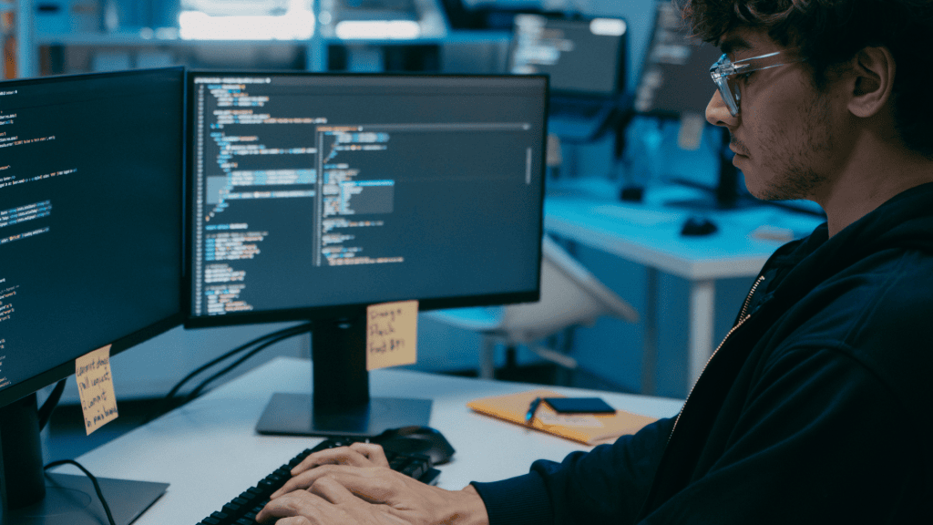 Joven programador trabajando en código en oficina tecnológica moderna.