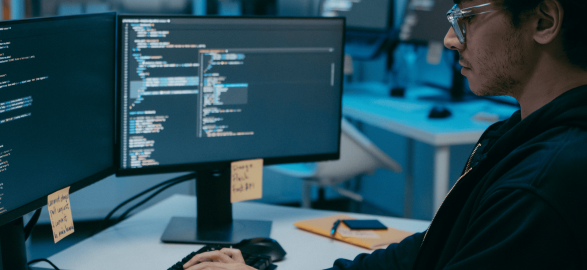 Joven programador trabajando en código en oficina tecnológica moderna.