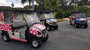 Disney-themed golf carts decked in vibrant colors parked near swaying palms at Walt Disney World, ready for magical adventures.