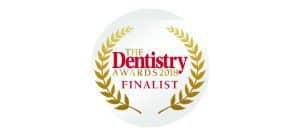 Home 16 The Dentistry Awards 2018 finalist badge featuring a gold laurel wreath and red text on a white background, symbolising excellence in dental care.