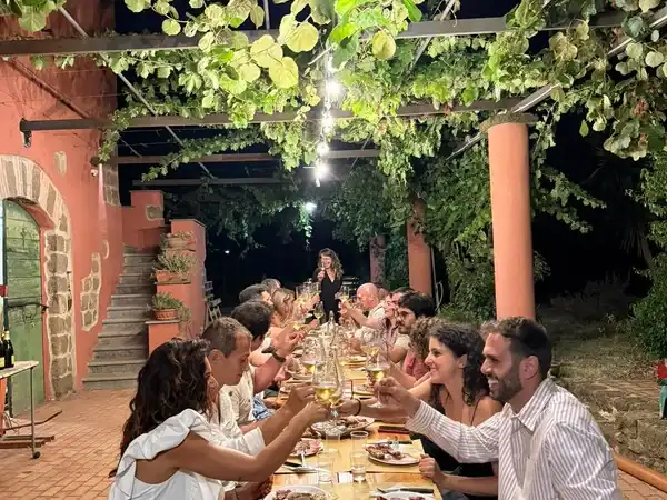 Gruppo di persone che degustano vino in un vigneto di notte.