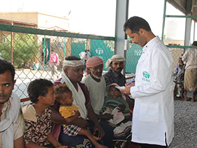 Spender verteilt medizinische Versorgung an wartende Menschen in einem Boat-Clinic-Projekt in Indien.