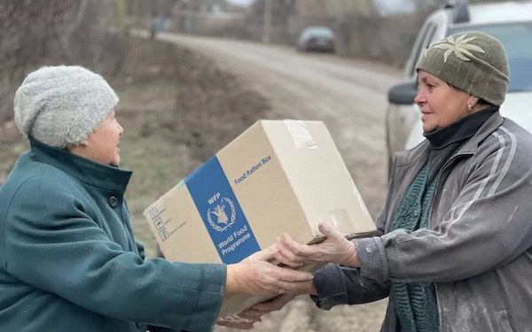 Hilfsorganisation verteilt Lebensmittelpaket an bedürftige Menschen, symbolisiert Unterstützung und Nächstenliebe.