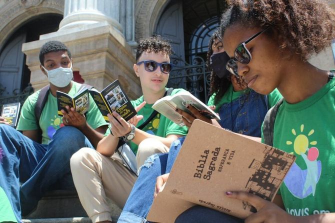 1. Familie liest gemeinsam Religionsbücher vor der Kirche, religiöse Bildung für Kinder, Glaube, Bibel, christliche Werte, Gemeindeleben, Advent-Verlag.