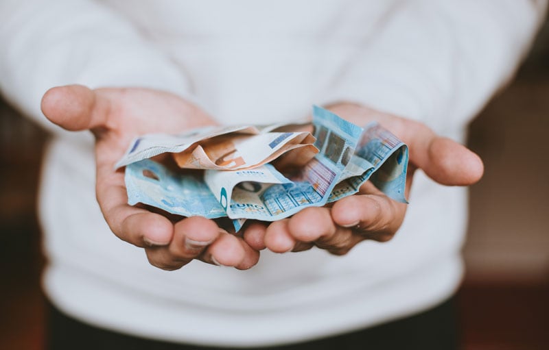 Kleine Hand hält zerknüllte Euro-Banknoten, Symbol für Geld, Finanzen, Wirtschaft, Sparen, Zahlungsmittel, Euro, Geldscheine, Geldmanagement, Finanzbildung, bei Advent-Verlag.