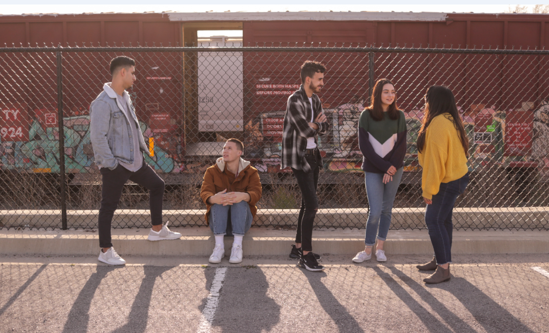 Gemeinschaft von jungen Menschen beim Gespräch an einer Bahnwagen im Freien, Symbol für soziale Interaktionen und urbanes Leben, passend für Advent-Verlag.