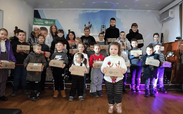 1. Jugendliche und Kinder bei einer Buchverteilung im Raum, mit Advent-Verlag Materialien und festlicher Atmosphäre, Fokus auf Kinderbuch-Event und Bildungsförderung.