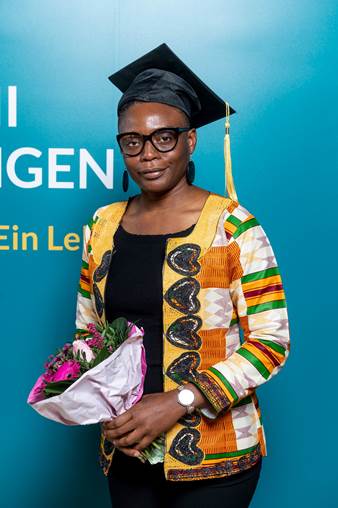 Erfolgreiche Absolventin in traditioneller afrikanischer Kleidung mit Doktorhut und Blumenstrauß, stolz und glücklich bei Abschlussfeier, symbolisiert Bildungserfolg und kulturelle Vielfalt.