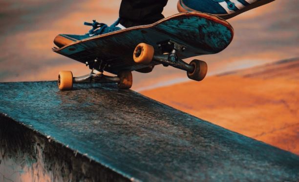Skateboard im Sprung bei Sunset, Actionfoto mit dynamischer Perspektive und warmem Himmelhintergrund.