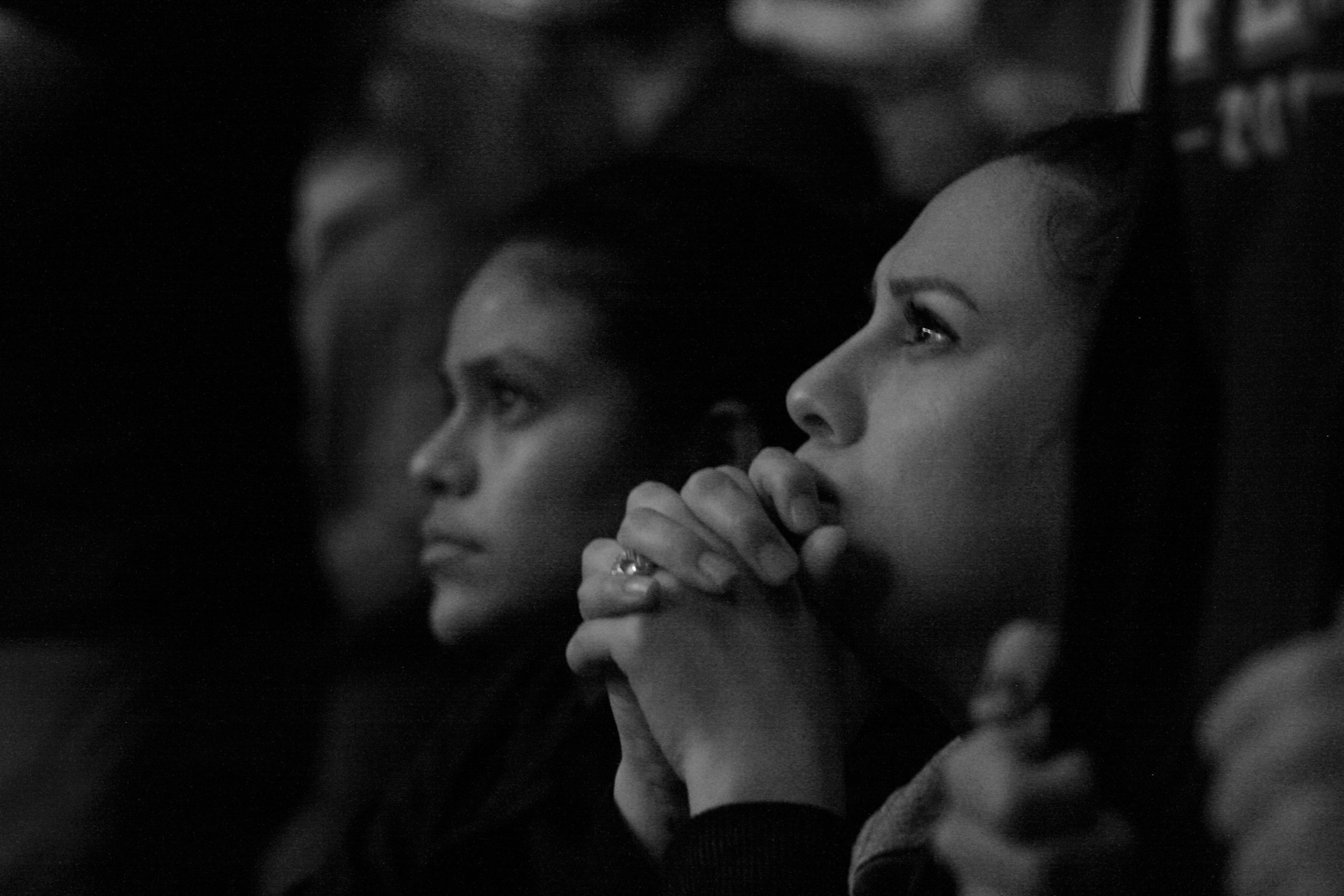 Betende Frauen bei einer religiösen Veranstaltung, Fokus auf Spiritualität und Glauben, calmante Atmosphäre, christliche Gemeinschaft, religiöse Praxis in Schwarz-Weiß.